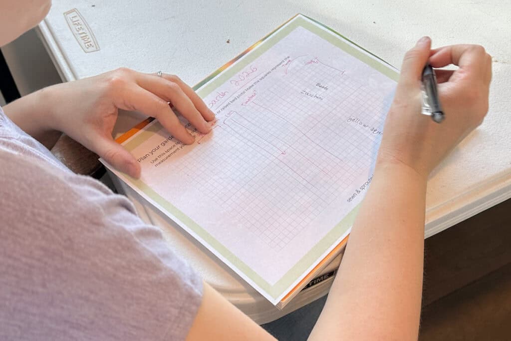 woman using simple garden planner to design her garden on paper