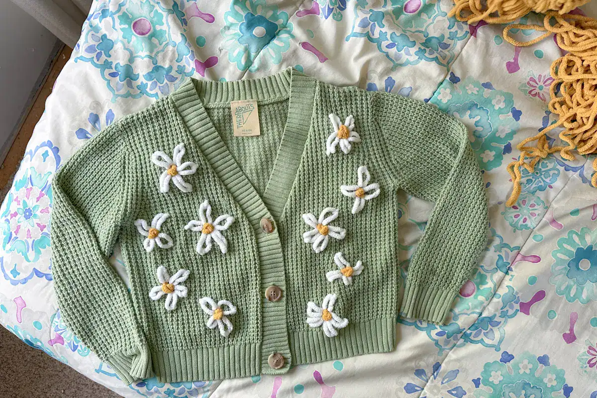 finished hand embroidered sweater, ten daisies stitched onto it.