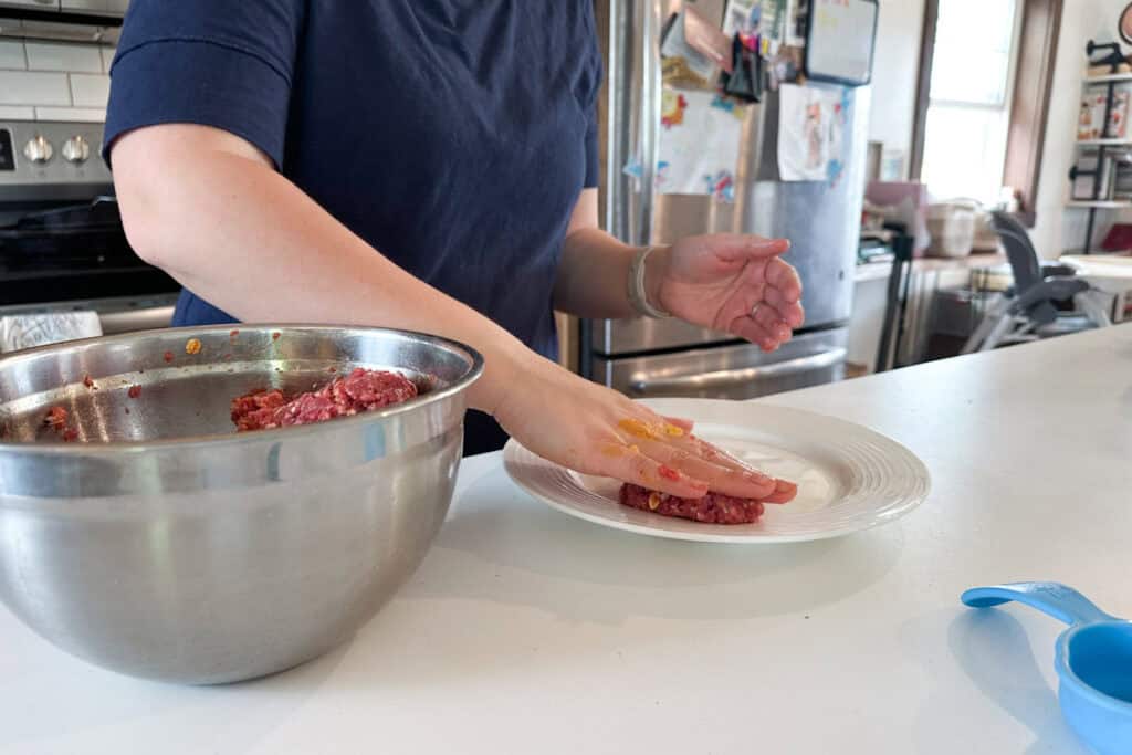 Marie shaping burgers and placing them on a plate.