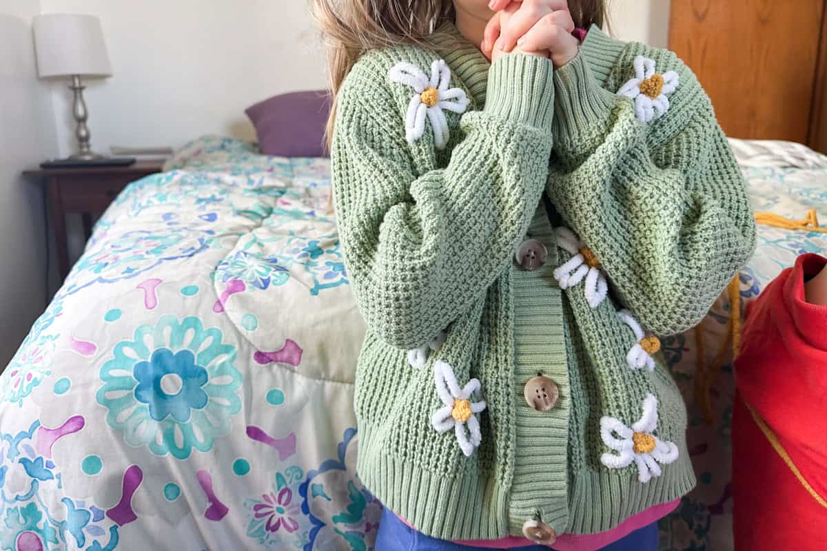 girl modeling finished sage green embroidered sweater with daisies